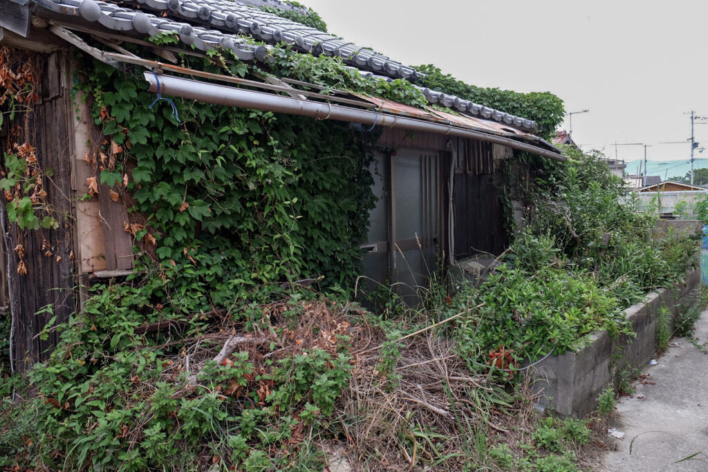 淡路島の古民家宿 AKIYA nehemiah。リノベーション前の草木に覆われた空き家の外観。